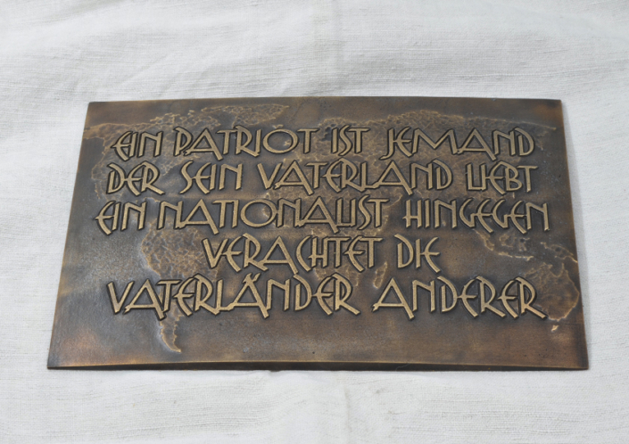 Bronzetafel mit erhabenem Text und der Weltkarte als Hintergrundrelief